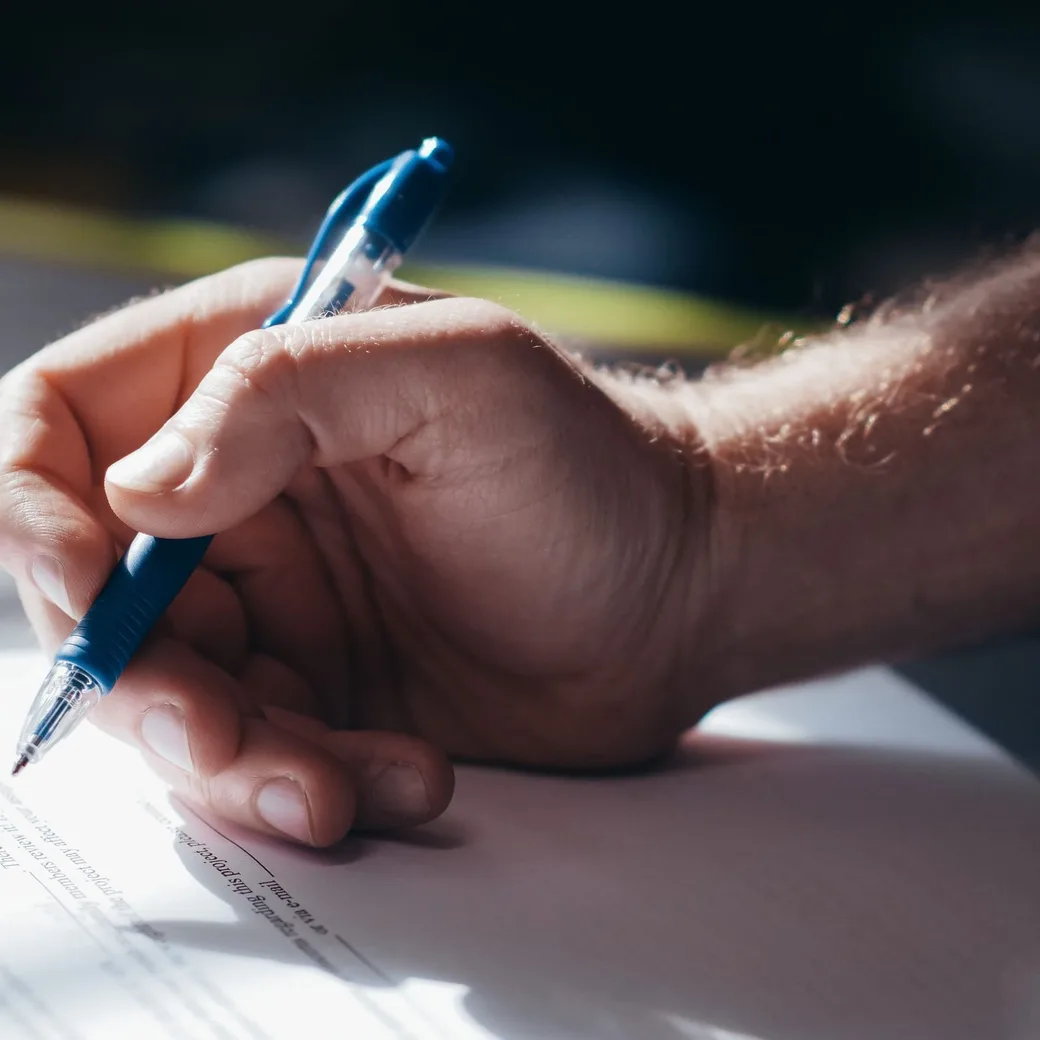Mano firmando un documento con un bolígrafo