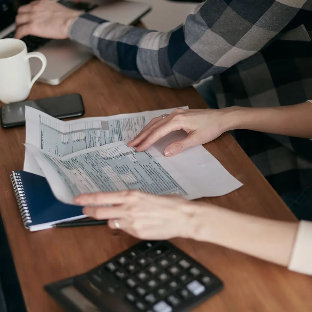 Manos revisando documentos fiscales junto a una calculadora
