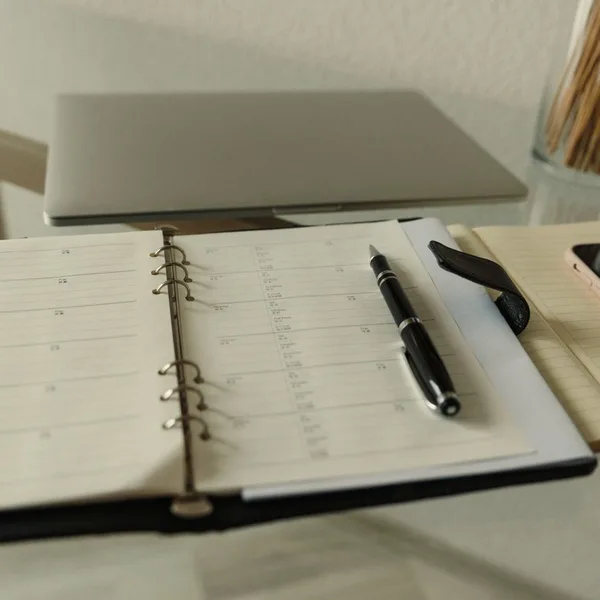 Una agenda de papel abierta con un bolígrafo sobre la mesa